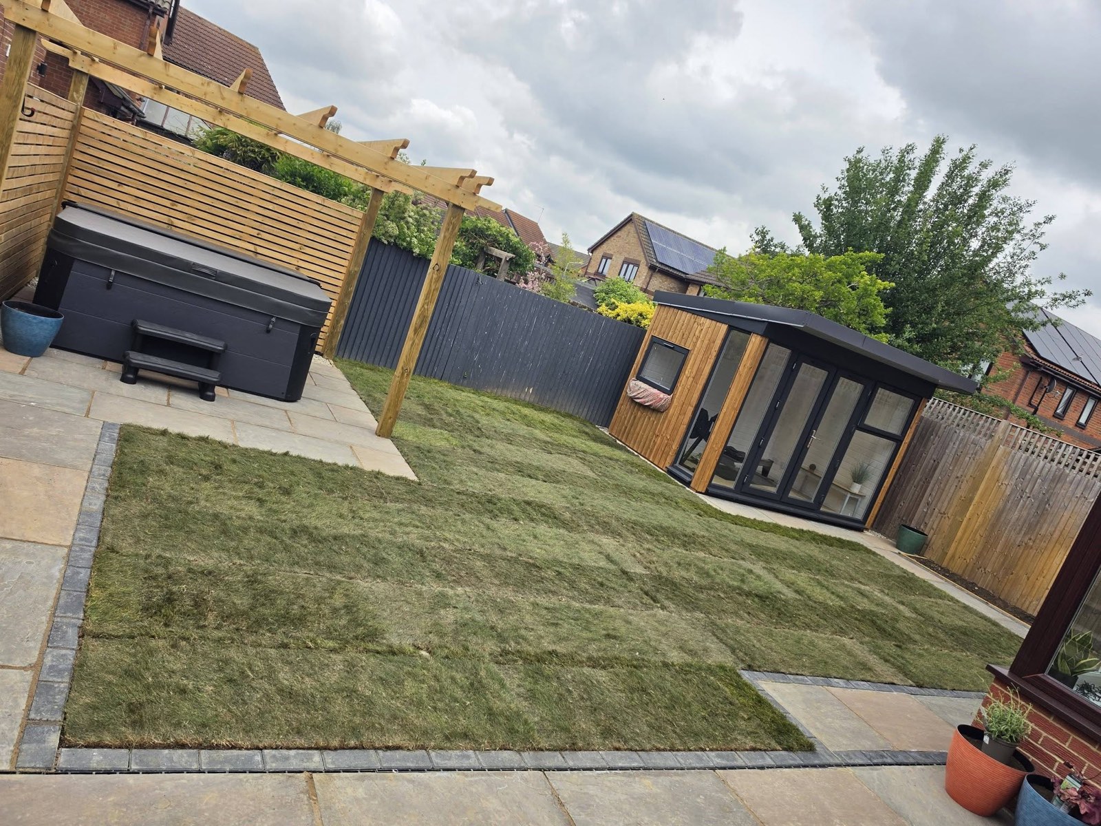 Completed garden makeover by Green Leaf Landscape Services with a new sandstone patio, freshly laid lawn, pergola and composite fencing